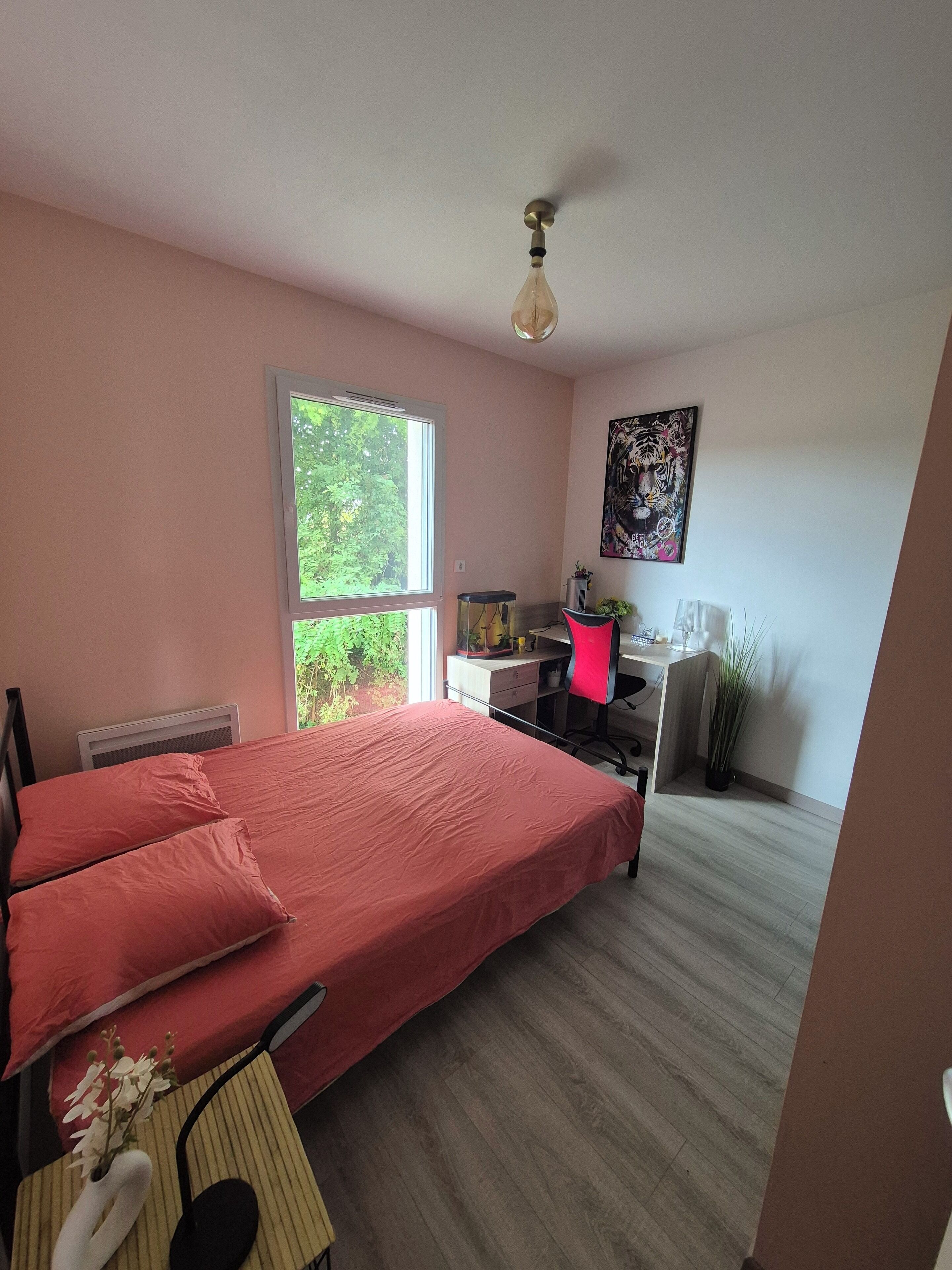 A bedroom with a bed, a desk, a chair, a window, and a ceiling fan.