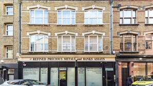 Un edificio con un cartello che indica 'Refined Precious Metals and Banks Assays' e un'auto parcheggiata davanti.