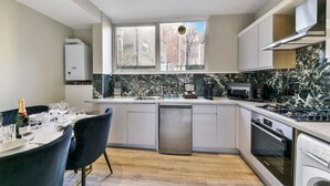 Una cucina moderna con zona pranzo, ampie finestre e vista sugli edifici.