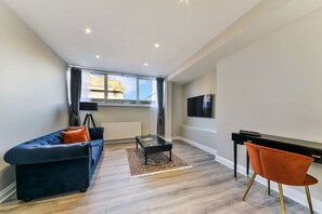A modern living room with a sofa, coffee table, and a TV mounted on the wall. - Avari - Luxury 2BR • Elegant Holborn Apartment (London)