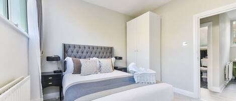 Ein modernes Schlafzimmer mit einem großen Bett, Nachttischen, einem Kleiderschrank und Blick ins Bad.