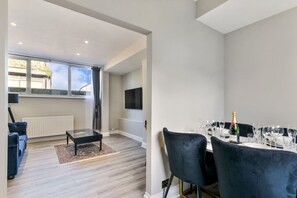 Ein modernes Wohnzimmer mit einer Couch, einem Couchtisch und einem Essbereich mit gedecktem Tisch.