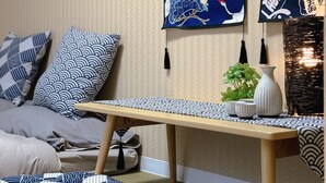 Ett rum med en traditionell japansk inredning, med ett golv av tatamimattor, ett lågt träbord och en upphängd rullgardin med ett motiv av en trana.