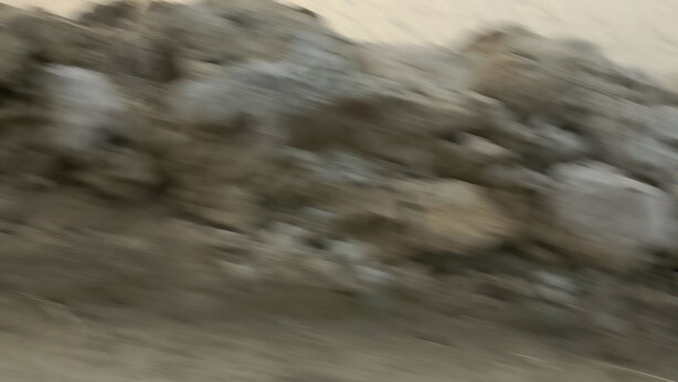 A blurred view of a construction site with piles of rocks and unfinished walls. - Ghgfgg (Singapore)