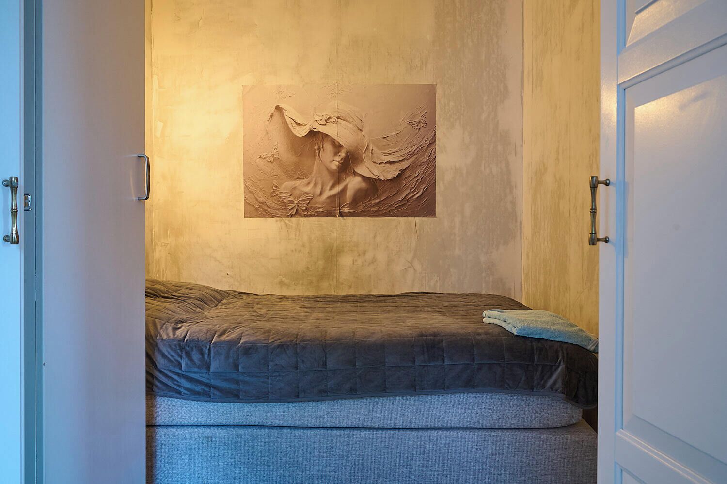 Un dormitorio con una cama, una obra de arte colgada en la pared y una puerta.