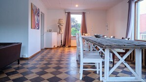 A dining area with a checkered floor, a wooden table, white chairs, a lamp, and a painting on the wall. - Spacious six-bedroom home.  Söderrasens National Park is only 23 miles away. (helsingborg)