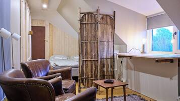 A room with a loft bed, a wooden chair, a small table, and a bamboo screen.