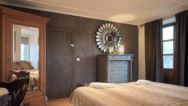 A bedroom with a large bed, a dresser, a mirror, and a window with curtains. - Spacious six-bedroom home.  Söderrasens National Park is only 23 miles away. (helsingborg)
