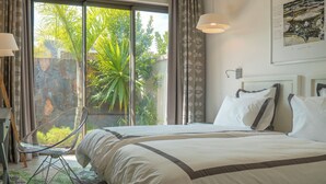 Une chambre à coucher comprenant un lit, un bureau, une chaise et une grande fenêtre donnant sur un paysage verdoyant.