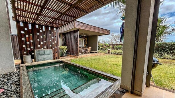 A pool area with a wooden pergola, a barbecue grill, and a grassy yard. - Luxurious & peaceful blend villa in Royal Park Balaclava Mauritius (Balaclava)