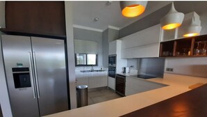 A modern kitchen with stainless steel appliances, a white countertop, and pendant lighting. - Luxurious & peaceful blend villa in Royal Park Balaclava Mauritius (Balaclava)