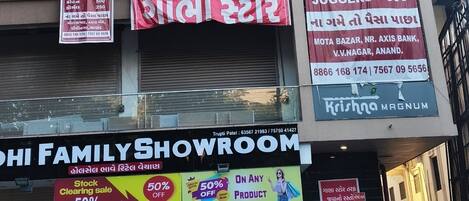 A multi-story building with various commercial establishments including a hotel named 'Hotel Rose Prime' on the third floor, a makeup salon, a store named 'Sabha Store', and a family showroom.