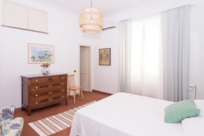 A bedroom with a bed, a dresser, a chair, a hanging light fixture, and two framed pictures on the wall. - Central and spacious apartment near St. Peter-Tiny House (Roma)
