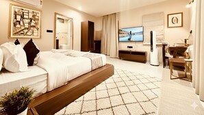 Ein modernes Hotelzimmer mit einem großen Bett, einem Flachbildfernseher, einem Schreibtisch und einer Sitzecke.
