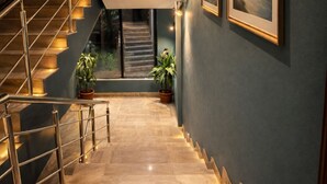 Eine moderne Treppe mit Metallgeländer, die zu einer zweiten Etage führt. Auf der Zwischenebene stehen zwei Kübelpflanzen.