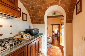 Una cocina equipada con estufa a gas, microondas y armarios de madera.