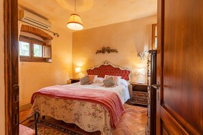 Une chambre à coucher avec un lit, une table de chevet, une lampe, une fenêtre avec des volets et une porte.