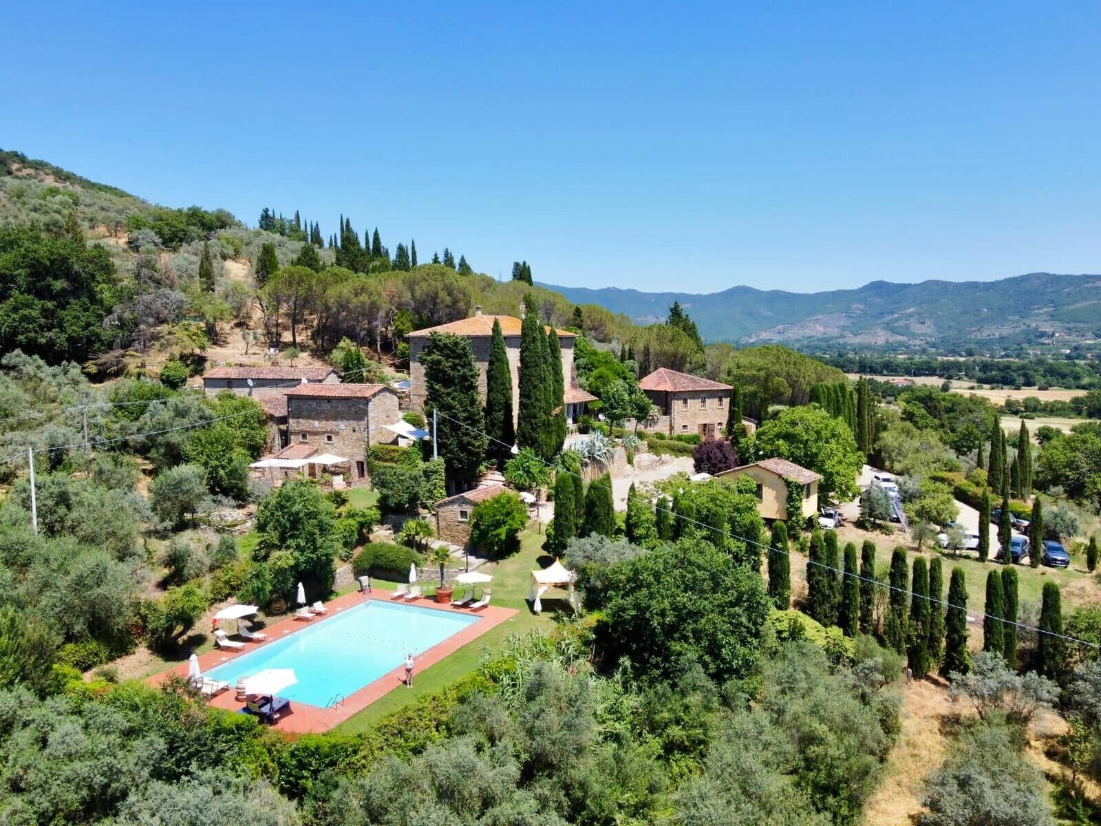 Eine Villa mit Swimmingpool, umgeben von üppiger Vegetation und Hügeln.