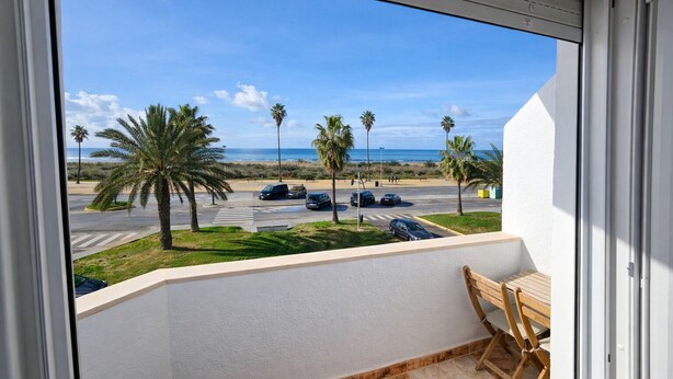 Un balcone con vista su un parcheggio, palme e una spiaggia.