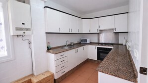 Una cucina compatta con mobili bianchi, un forno a microonde, un fornello e un lavello.
