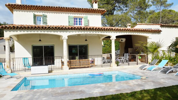 Una casa de dos pisos con piscina, mobiliario exterior y jardín.