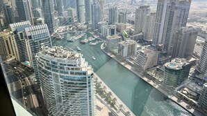 Un edificio alto con un puerto deportivo y una vía fluvial en primer plano, rodeado de otros edificios elevados.