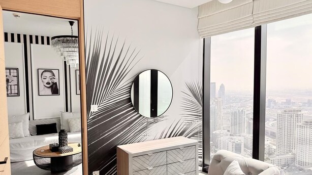 Un dormitorio moderno con una cama grande, un espejo redondo, una mesita de noche y vistas a la ciudad.