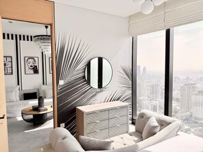 Quarto moderno com uma cama grande, um espelho redondo, mesa de cabeceira e vista para a cidade.