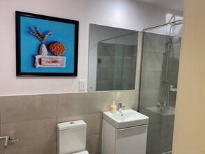 A modern bathroom with a toilet, sink, and glass shower enclosure. - 3As Properties (Accra)