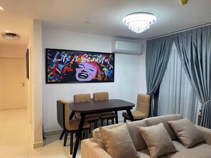 A modern living room with a dining area, a large wall-mounted TV, and a chandelier. - 3As Properties (Accra)