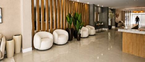 A spacious lobby with a reception desk, seating area, and a large potted plant.