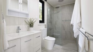 A modern bathroom with a shower, toilet, sink, and cabinets. - Wood Duck Daylesford (Daylesford)