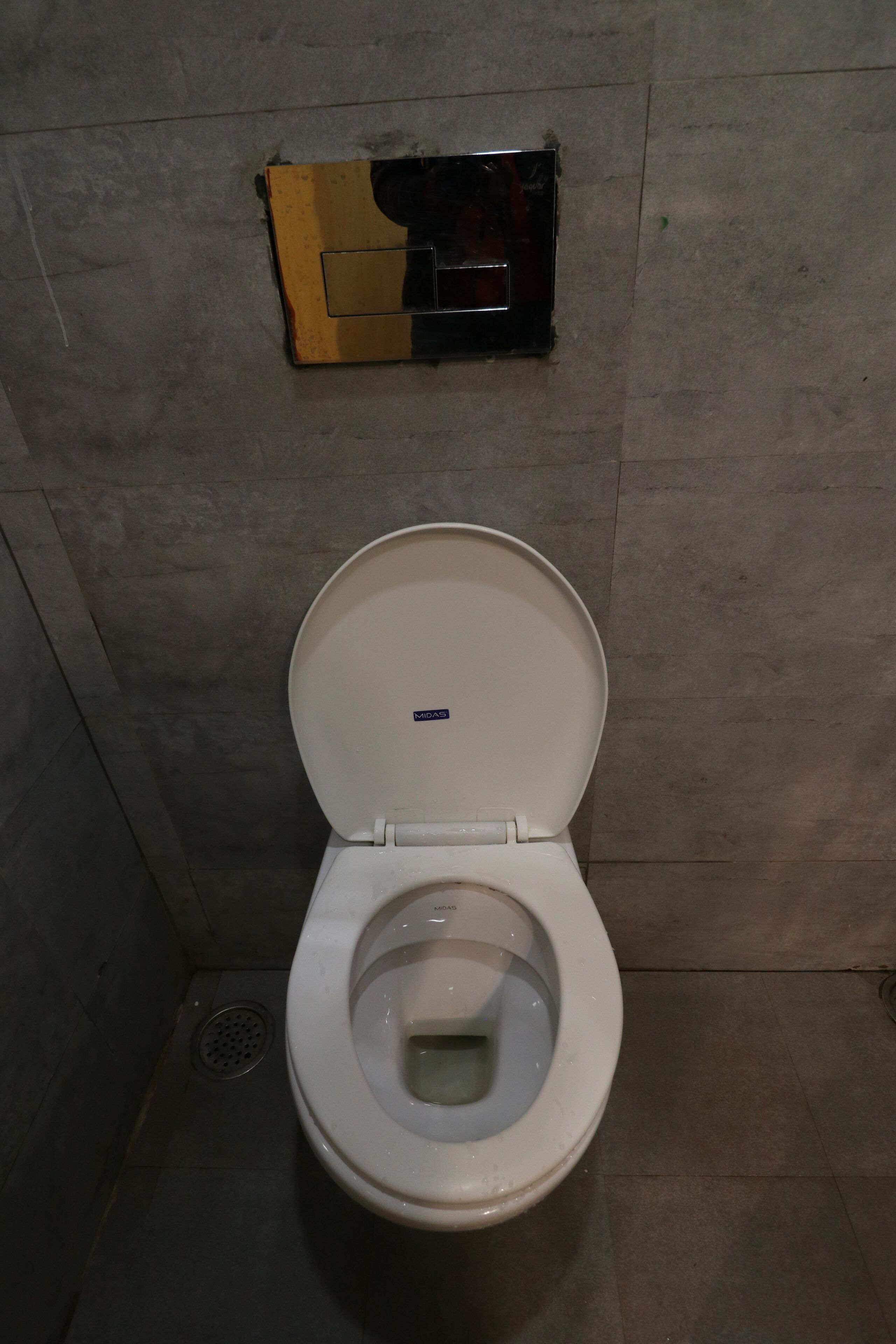 A white toilet with a closed lid in a bathroom with tiled walls and a floor.