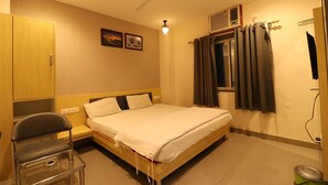 Une chambre d’hôtel avec un lit, une chaise, un ventilateur de plafond et une fenêtre avec des rideaux.