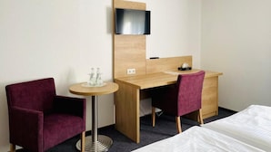 A hotel room with a wooden desk, two chairs, a TV mounted on the wall, and a bed. - Hotel Esmer (Lollar)