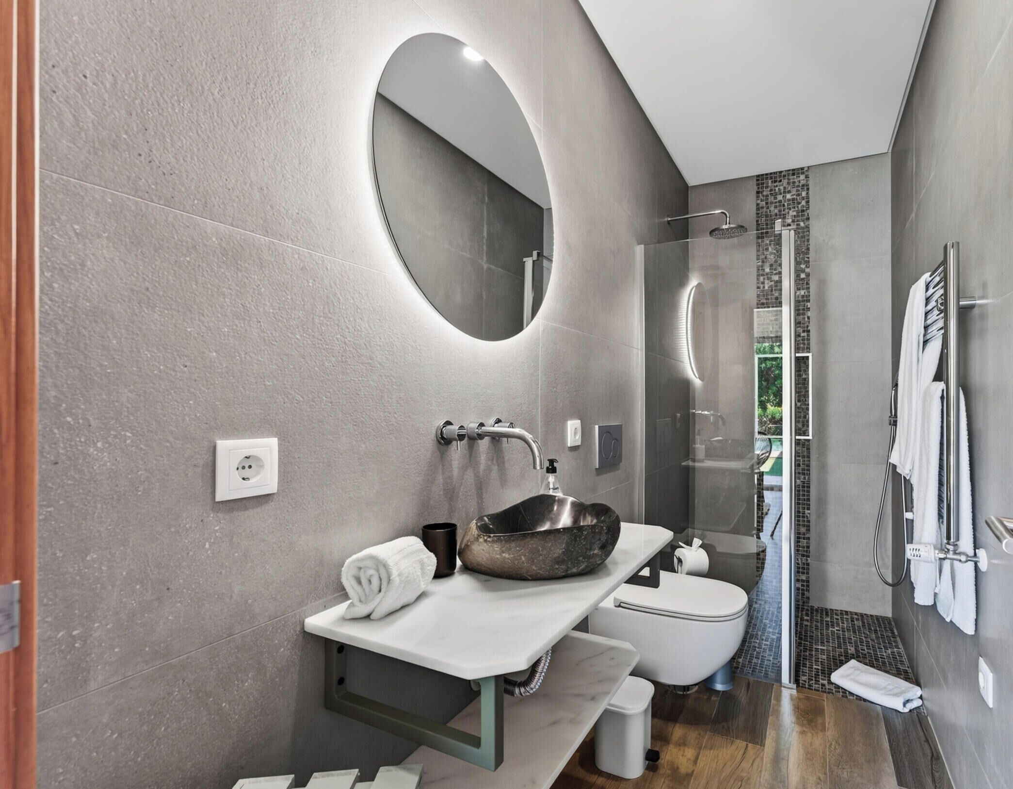 Un baño moderno con un espejo grande, un lavabo con una pila original, un inodoro y una zona de ducha.