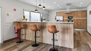 Une cuisine moderne dotée d’un îlot central, de tabourets de bar et de luminaires suspendus.