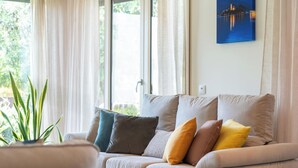 Un salon avec un canapé, une plante en pot et un tableau accroché au mur.