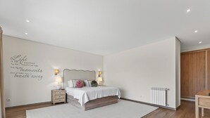 Une chambre à coucher avec un lit, des tables de chevet, un mur orné d’une citation, un radiateur et une armoire en bois.