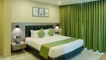 A hotel room with a large bed, green curtains, and a nightstand with a phone.