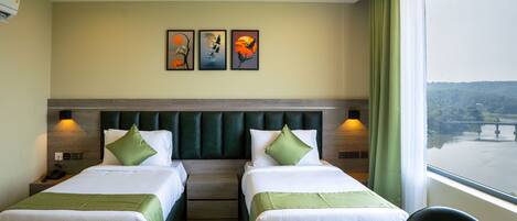 A hotel room with two beds, a large window with a view, and artwork on the wall.