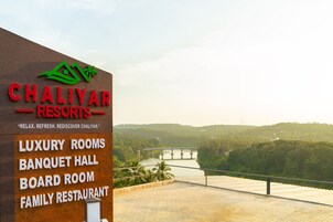 Cartel de Chaliyar Resorts que enumera servicios como habitaciones de lujo, salón de banquetes, sala de reuniones y restaurante familiar.
