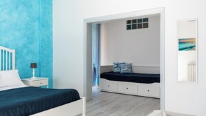 A modern bedroom with a bed, nightstand, and a view of a room with a bed and a window. - Quadruple room at 25 rimini street within walking distance of serapo beach VOLARE (Gaeta)