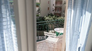 A balcony with a white chair, a small round table, and a green railing. - Quadruple room at 25 rimini street within walking distance of serapo beach VOLARE (Gaeta)