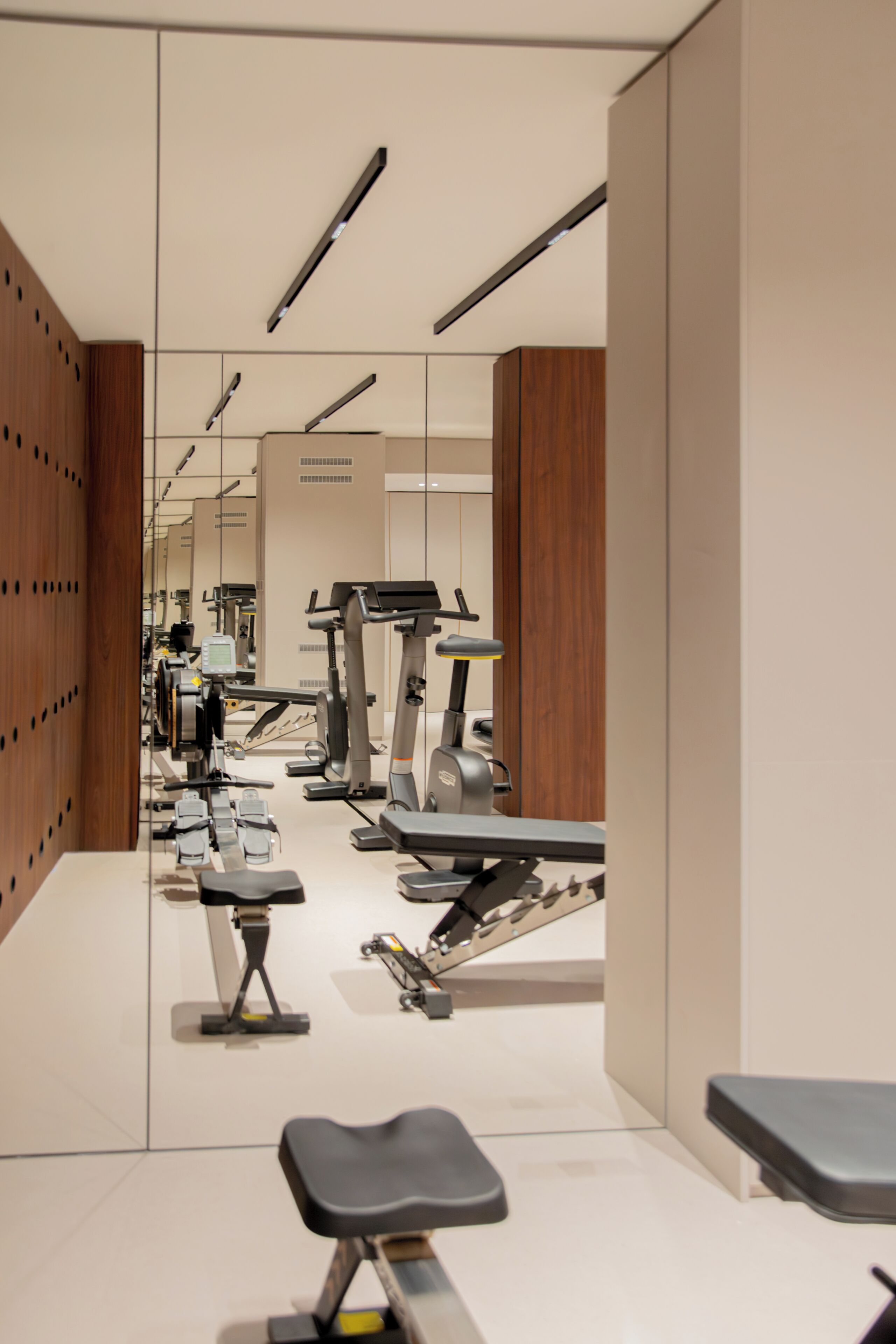 Une salle de sport équipée de matériel d’exercice, dotée d’un mur avec des miroirs et d’un mur recouvert de panneaux en bois.