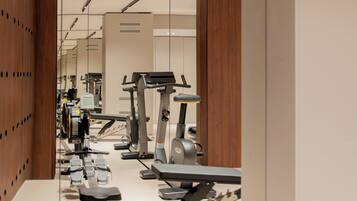Une salle de sport équipée de matériel d’exercice, dotée d’un mur avec des miroirs et d’un mur recouvert de panneaux en bois.
