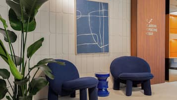 Un intérieur moderne avec deux chaises bleues, un tabouret bleu et une œuvre d’art abstraite accrochée au mur.