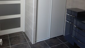 A bathroom with a white door, dark tiles, and a dark-colored sink. - Holiday in the Sun and Sea, Apartment on 1st or 2nd floor! (Elne)