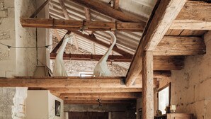 A rustic interior with exposed wooden beams, a long dining table, and a stone wall. - Bastide with garden and swimming pool 10 minutes from Saint Rémy de Provence (Eyragues)