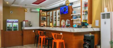 A bar area with a counter, bar stools, and a television screen.